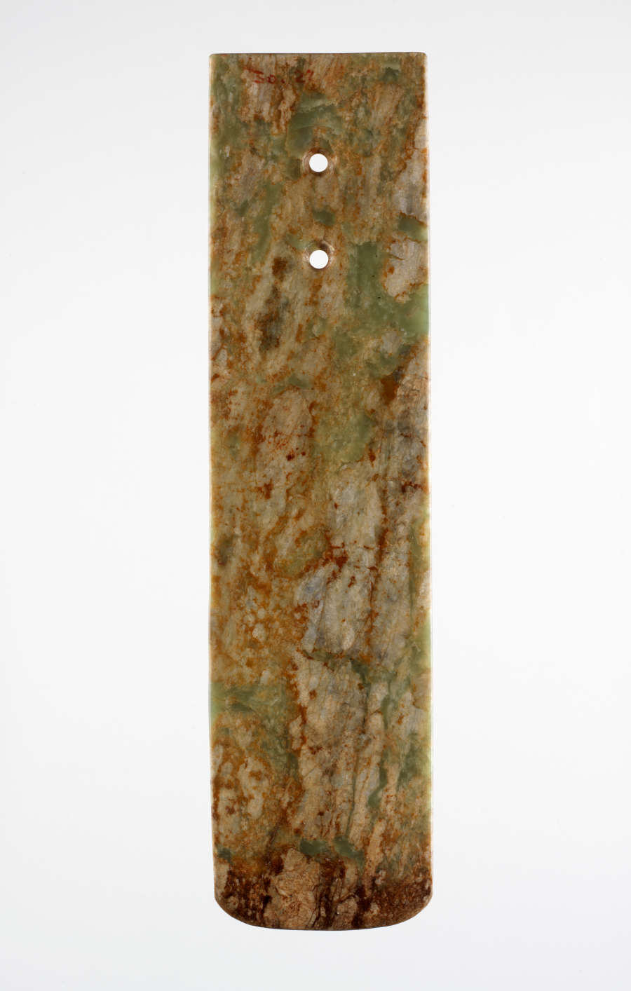 A long, rectangular stone blade with two holes punched below its top edge. The bottom edge is slightly rounded. The blade is a smooth, marbled green and brown texture.