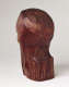 Three quarter back view of a carved wood sculpture depicting the back of a head and neck. Part of a cheekbone and brownbone are visible towards the front. The signature “Elizabeth Prophet” is thinly carved into the neck.