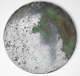 Front of the round corroded bronze mirror. Its polished surface is spotted with dark brown and large patches of flaky green corrosion.
