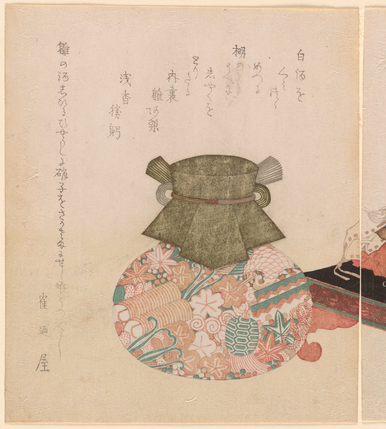 A colorfully decorated round jar, the top sealed with fabric, below columns of calligraphic text and the edge of furniture on right.