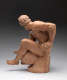 Realistic terracotta sculpture depicting a muscular bearded man facing away to the left, his bent arm supporting him while his leg sits over a vessel he bends down to hold.
