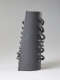 Side view of a cylindrical gray ceramic sculpture featuring a row of protruding loops threaded along its periphery. The opposing side is flat with similar forms organized in a row.