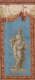 Sculptural figure draped in flowing robes holding a cup in one hand and a wheat bundle in the other. An elaborate terracotta border frames the figure and the blue background.