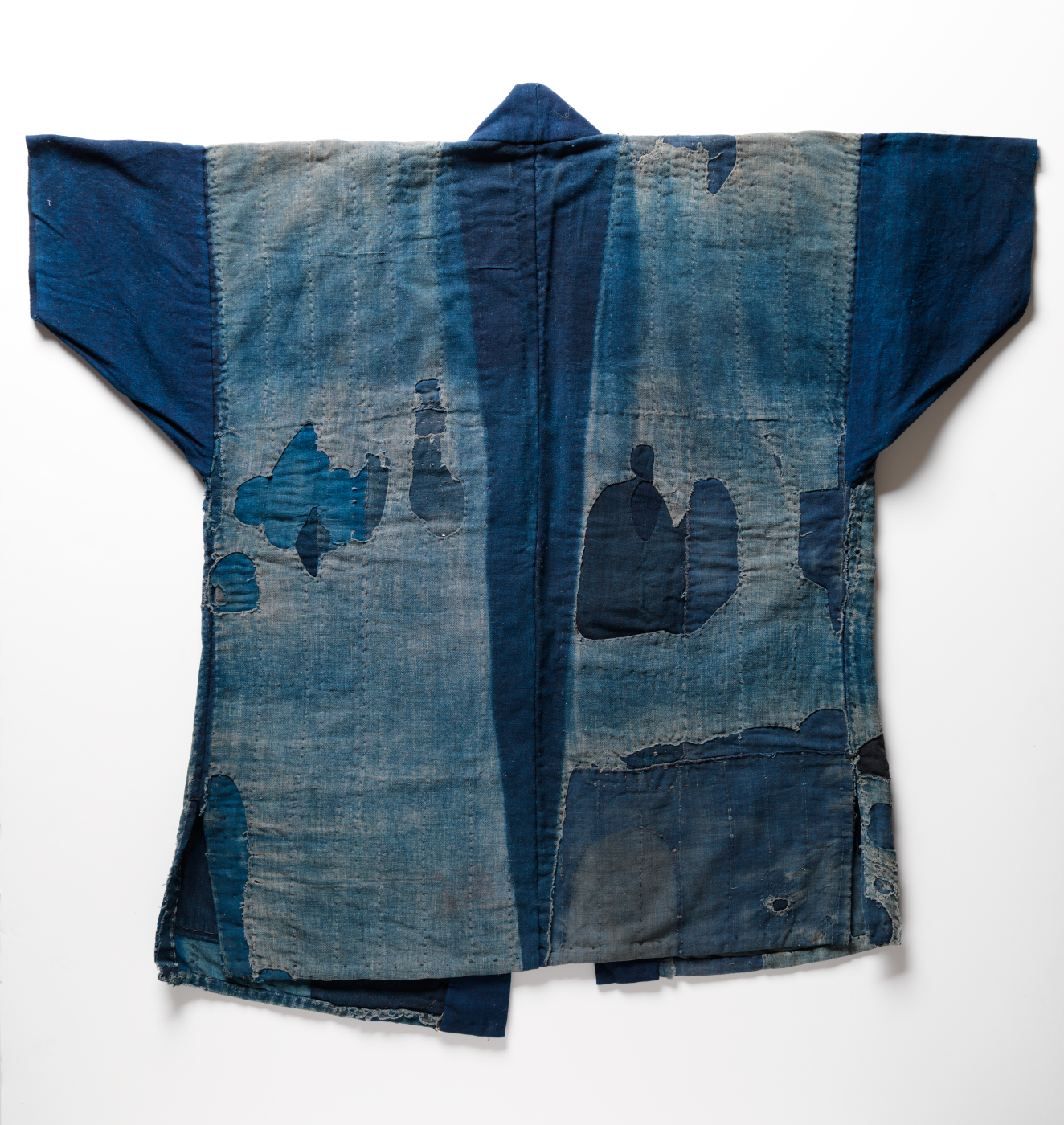 Back view of an indigo jacket with patchwork and visible fading.