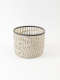 Delicate white basket-like cup constructed of intersecting lattices forming an airy woven grid with narrow open slats and a dark gray edge around the opening.