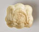 A cream-colored sculptural mold. It is curved with inset floral and bow decorations.