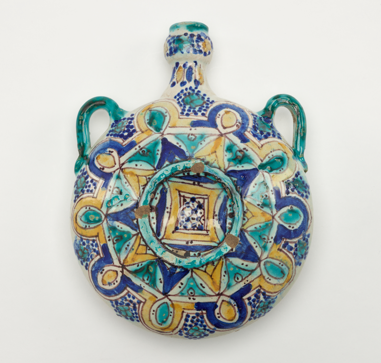 A completely rounded bottle with a neck and two symmetrical handles. There are symmetrical decorations that are dark blue, turquoise, and yellow.