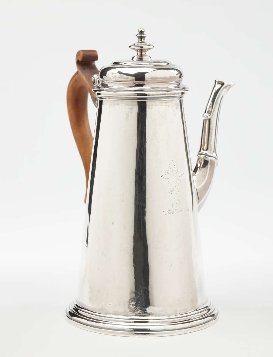 A silver chocolate pot with a spout, hinged lid, and fruitwood handle that is 90 degrees from the spout.
