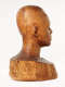 Three quarter back view of a glossy wooden bust depicting the head of a male figure. The wood has smooth contours, long vertical cracks, carving marks and color variation.