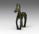 Front-view of a bronze horse figurine with a green patina, and an exaggeratedly thin torso, thick neck, long legs and tail and long narrow snout.