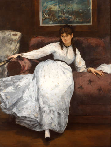 A woman with dark hair and a calm expression reclines in a long white dress on a red sofa, one arm outstretched holding a fan, beneath a framed blue turbulent seascape painting.