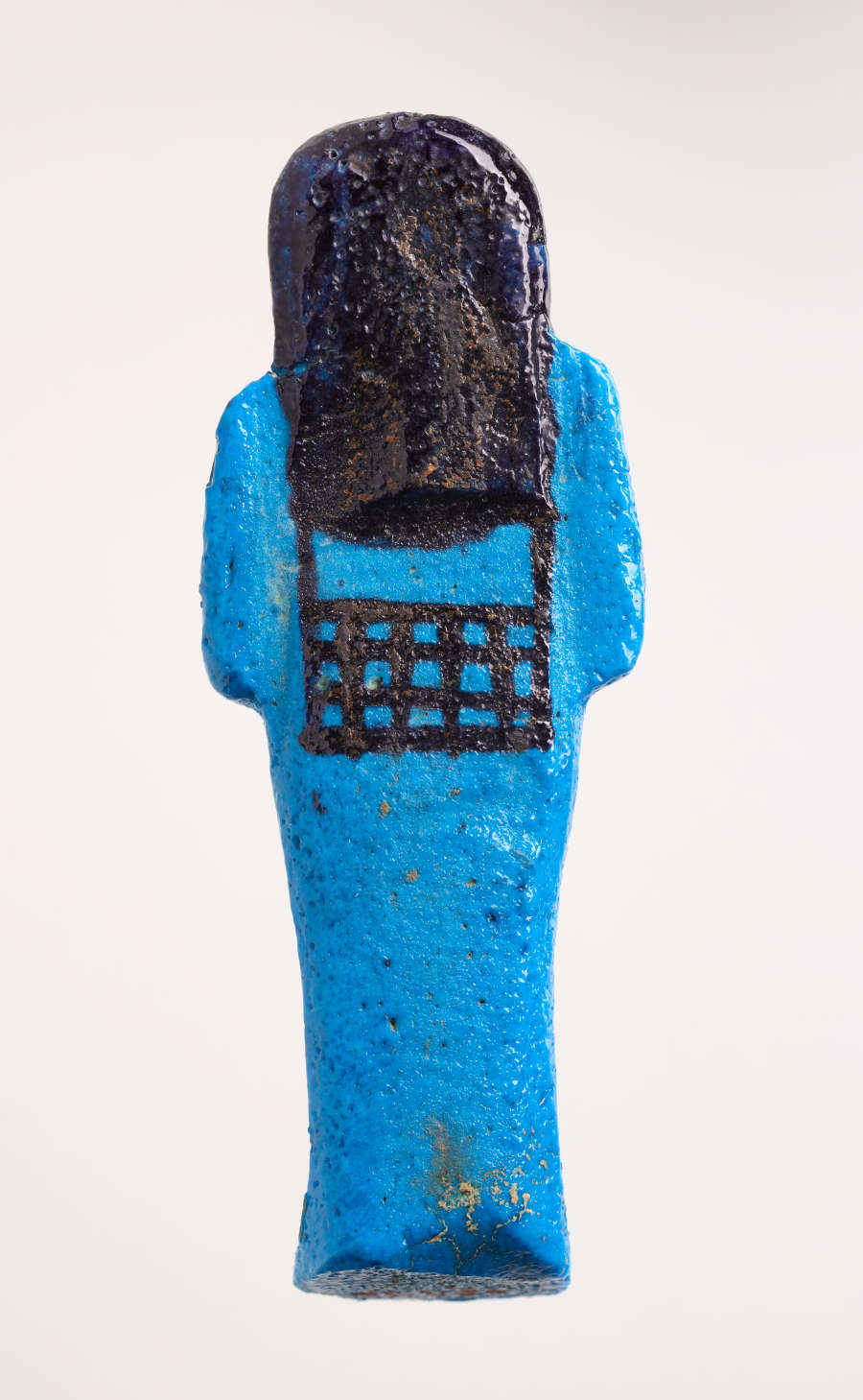 Back of a blue sculpture of a reclining mummy-like figure laid horizontally, with its hand laid on its chest and black detailing of its hair and ornamentation.