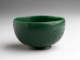 A rounded, green colored vessel with incised floral designs.