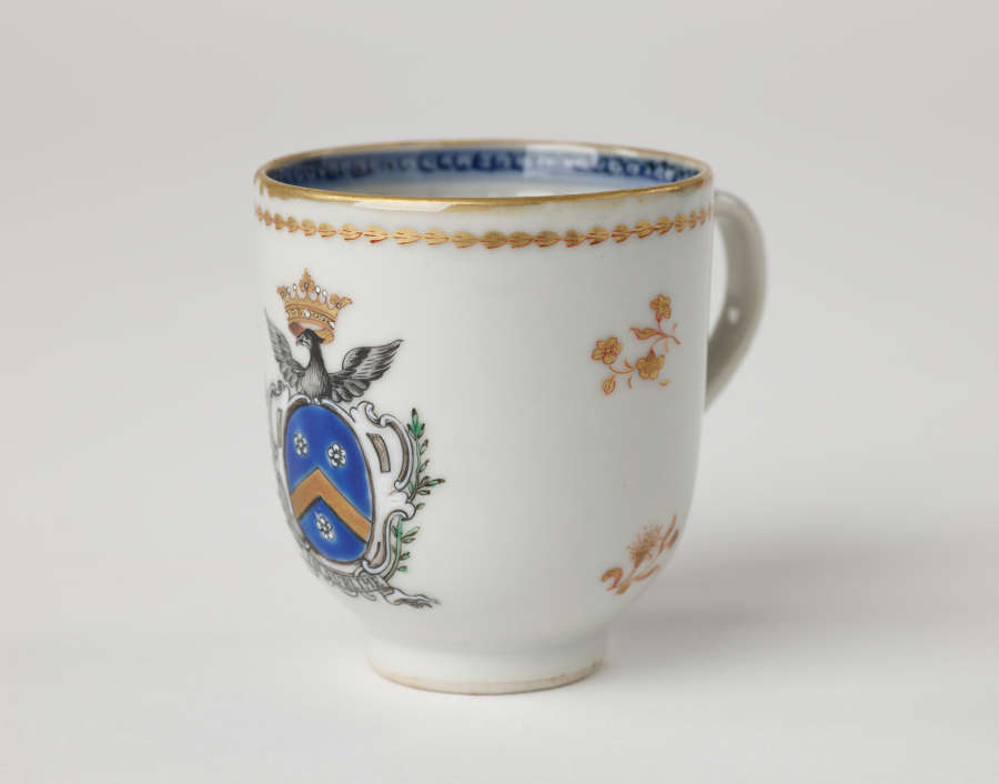 A cup with blue and gilded decorations along the outside and inside of the rim, body, and handle.