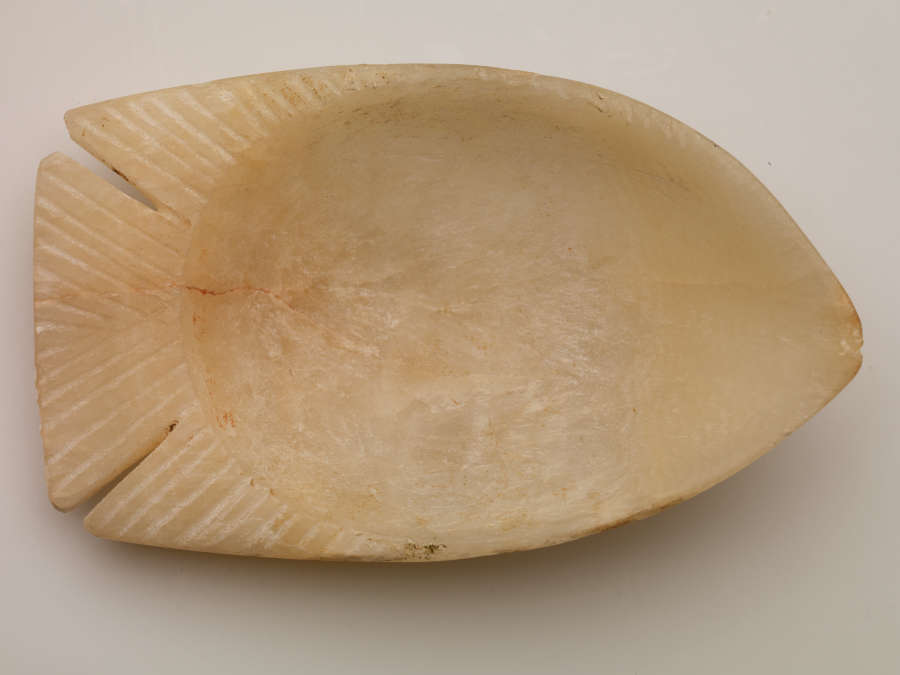 Top view of the tan bowl, showing that the edge of the bowl is shaped like the tail and fins of the fish, with carved lines adding detail to the fins.