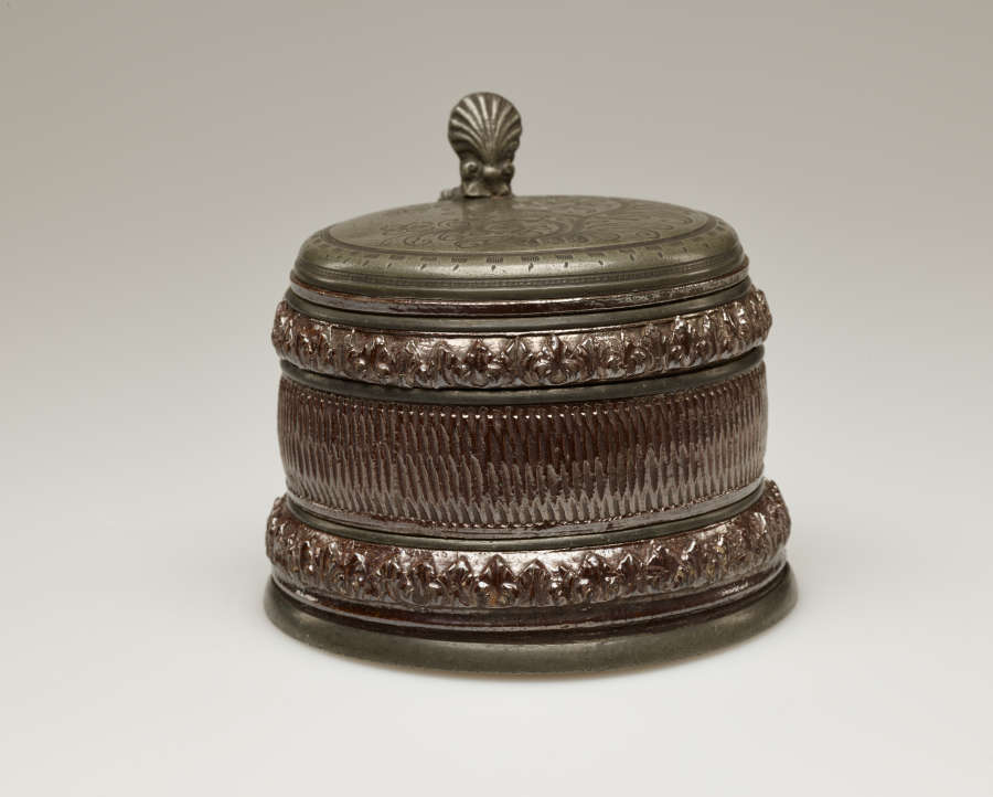 A brown and tan mug with a silver, scalloped rim.