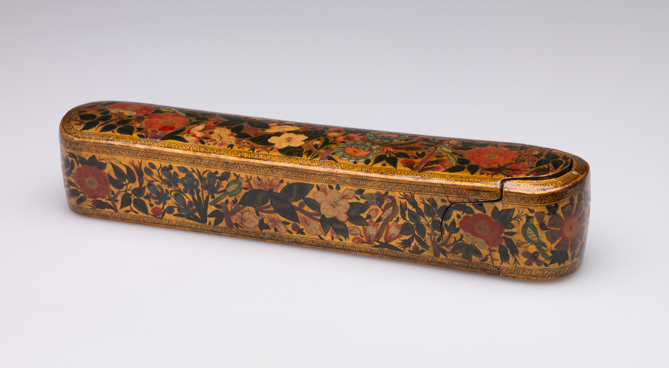 A long, rectangular lacquered golden case with rounded corners whose surface sports a lush pattern of red and white flowers surrounded by deep green leaves and intricate gold borders.