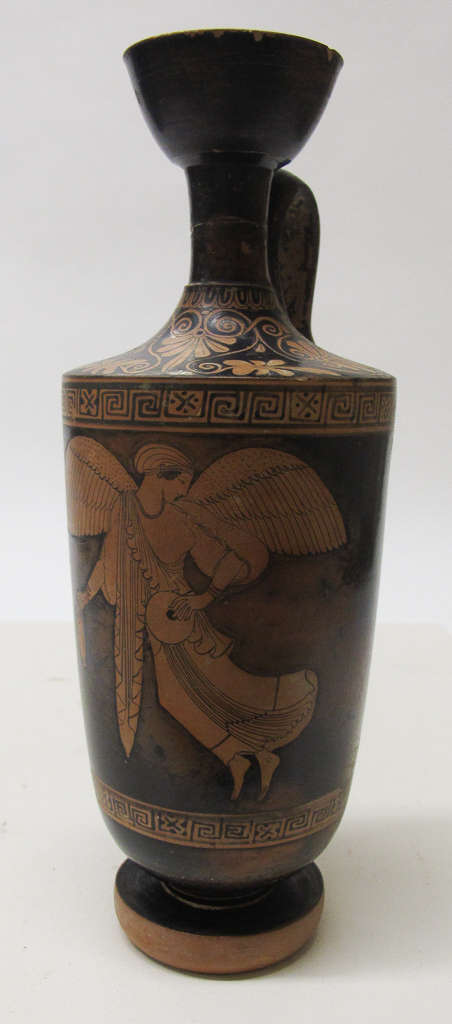 Tall black vessel with a narrow neck and handle decorated by designs in orange depicting dense, flowing patterns above a robed winged figure framed by geometric spiraling patterns.