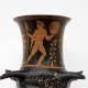 Close-up of the flared neck of a black ceramic vessel, featuring a painting of a red, nude, muscular figure holding a wheat-like staff and round shield, framed by floral patterns. 