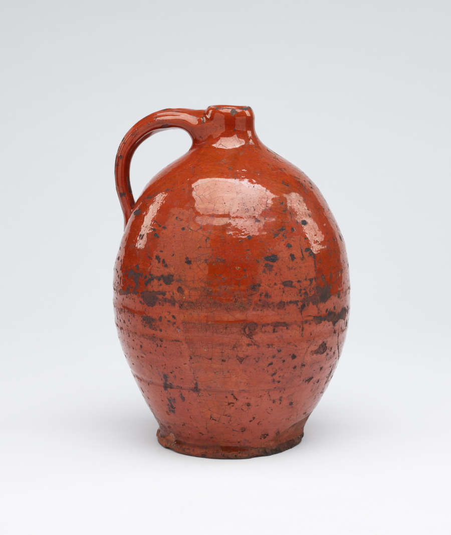 A bulbous orange ceramic jug with a handle.