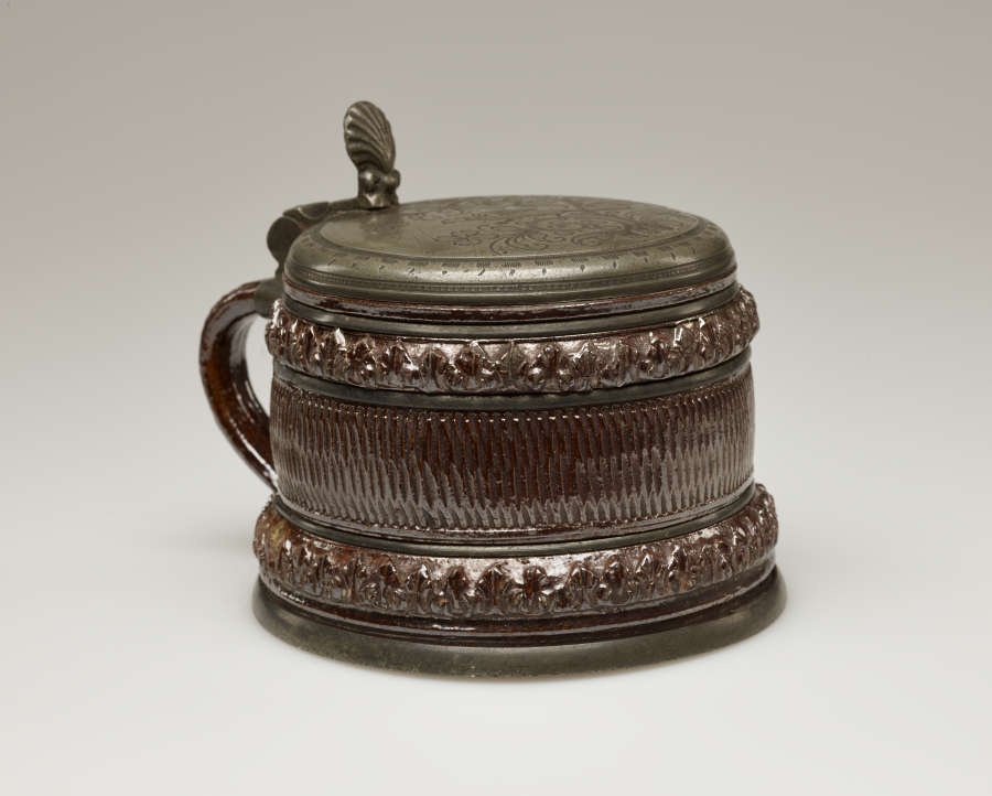 A brown and tan mug with a silver, scalloped rim.