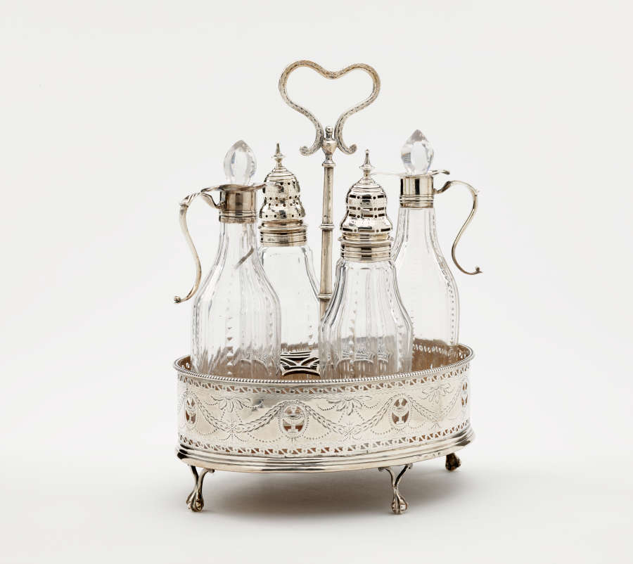 A silver container with small feet and a curved, open handle on top. Inside are several glass vessels with silver mounts.