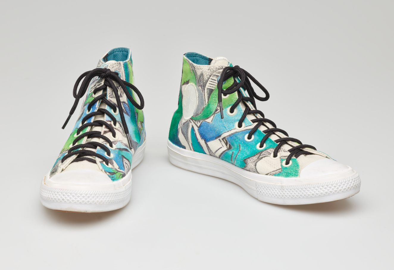 High top sneakers with a bright hand-painted blue and green abstract design and black laces.