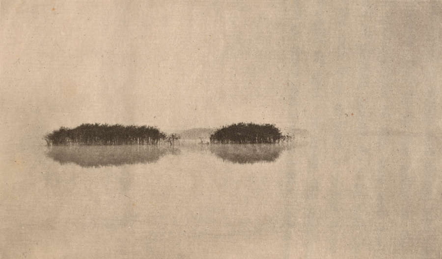 A minimal image depicting two dark islands and their calm, watery reflections.