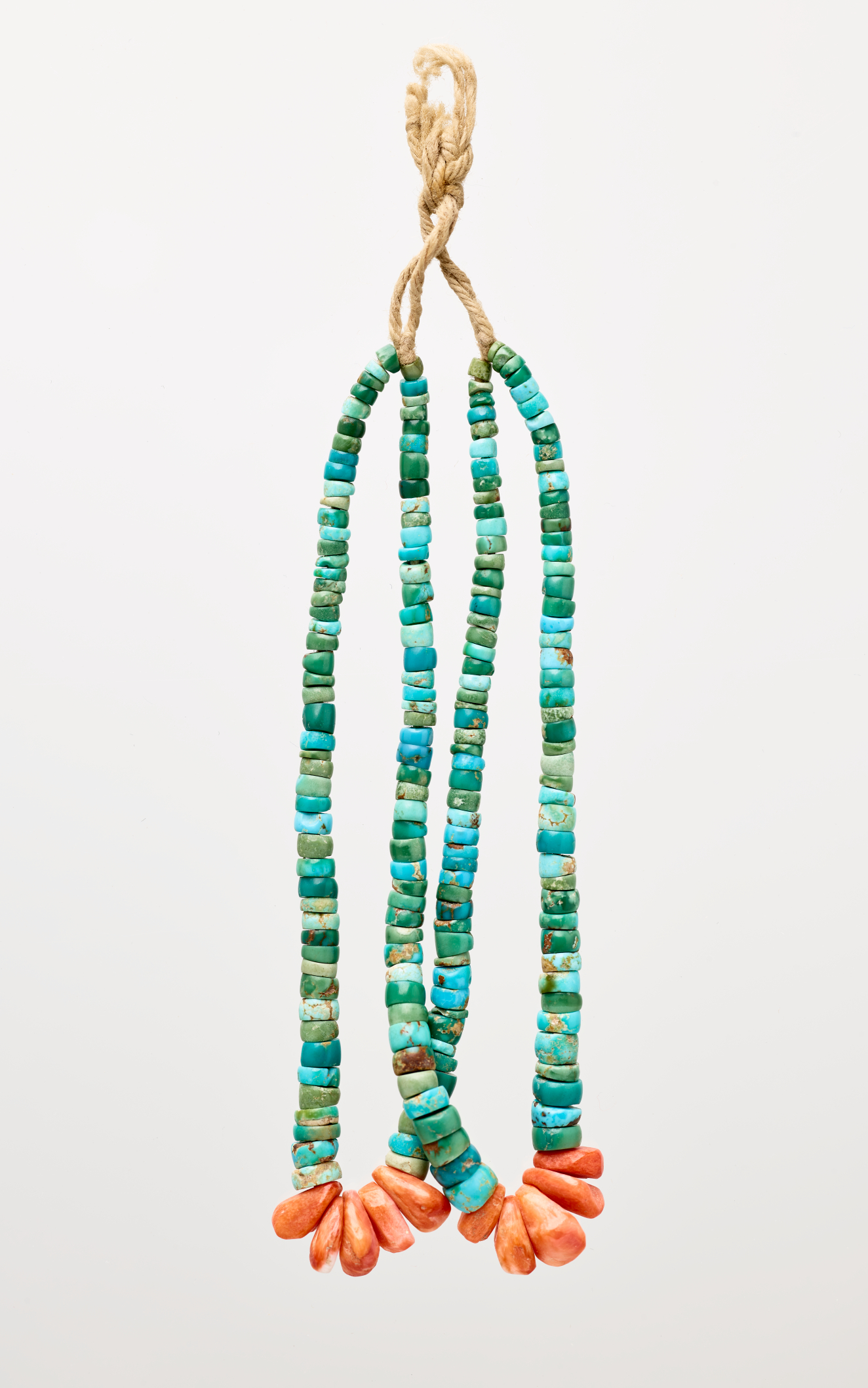 Earring with a twine-like hook connecting to two loops of flat, circular turquoise beads, with kernel-like red beads at each loop’s base.
