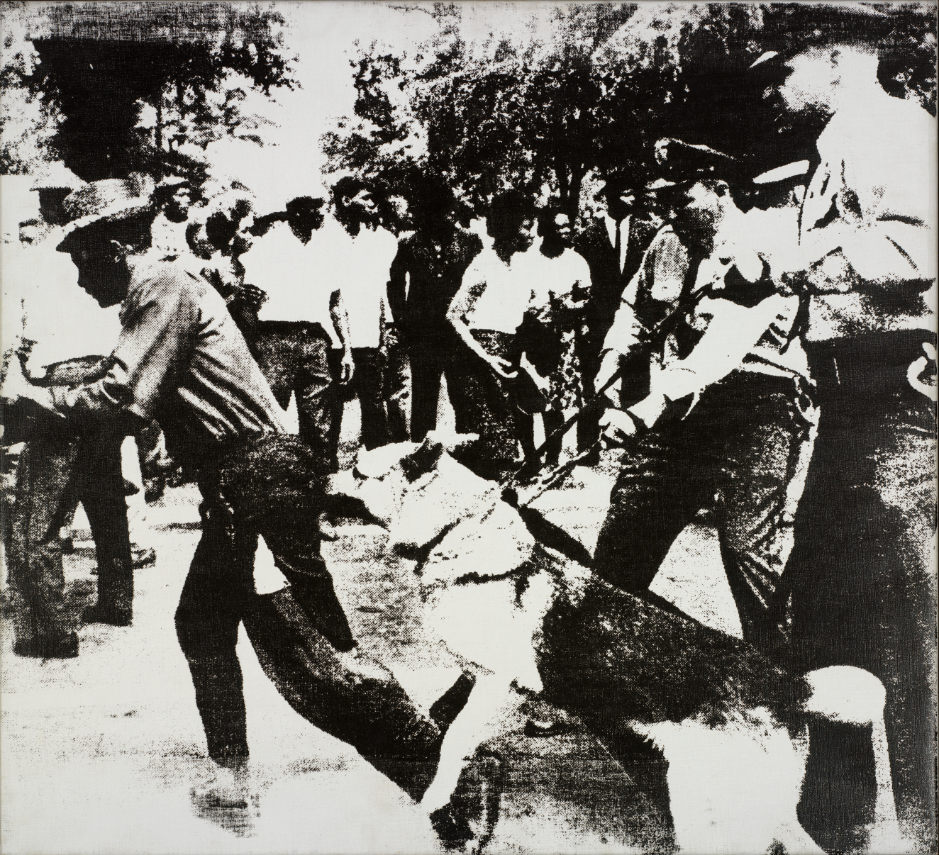 A grainy, black-and-white scene of a dark-skinned man being attacked by large dogs slightly restrained by two light-skinned police officers while a crowd looks on in the background. 