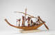 A painted wooden model of a boat with eight figures rowing and working around a mast.