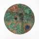 Front of an ornate circular mirror, with a surface corroded into moss-like blues, greens, and brown patches which blend into one another.
