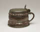 A brown and tan mug with a silver, scalloped rim.