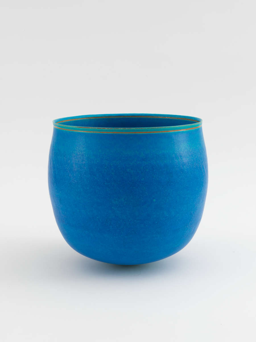 Smooth, rounded ceramic cup with a polished, vivid blue matte surface, its rim neatly accented by a thin green band encircling the opening.