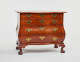 A polished wooden dresser with four curved drawers, ornate metal hardware, and intricately carved claw feet.