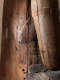 Close up of an aged wooden statue, showing cracks, metal reinforcements, and visible signs of wear.