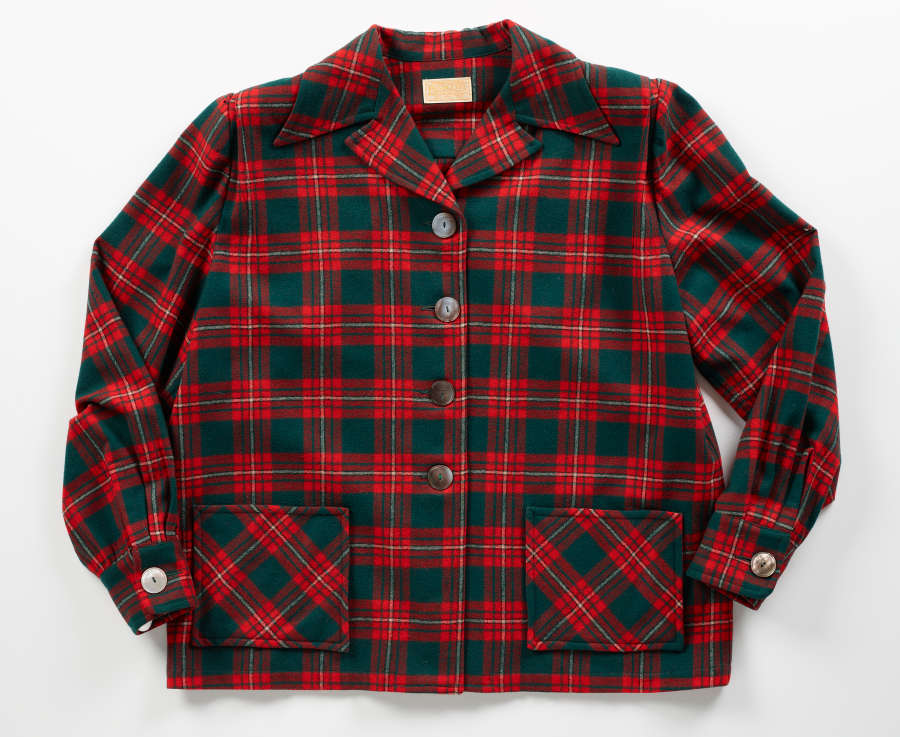 Buttoned red and green plaid long-sleeved shirt with two front pockets and a collar, laid flat. 