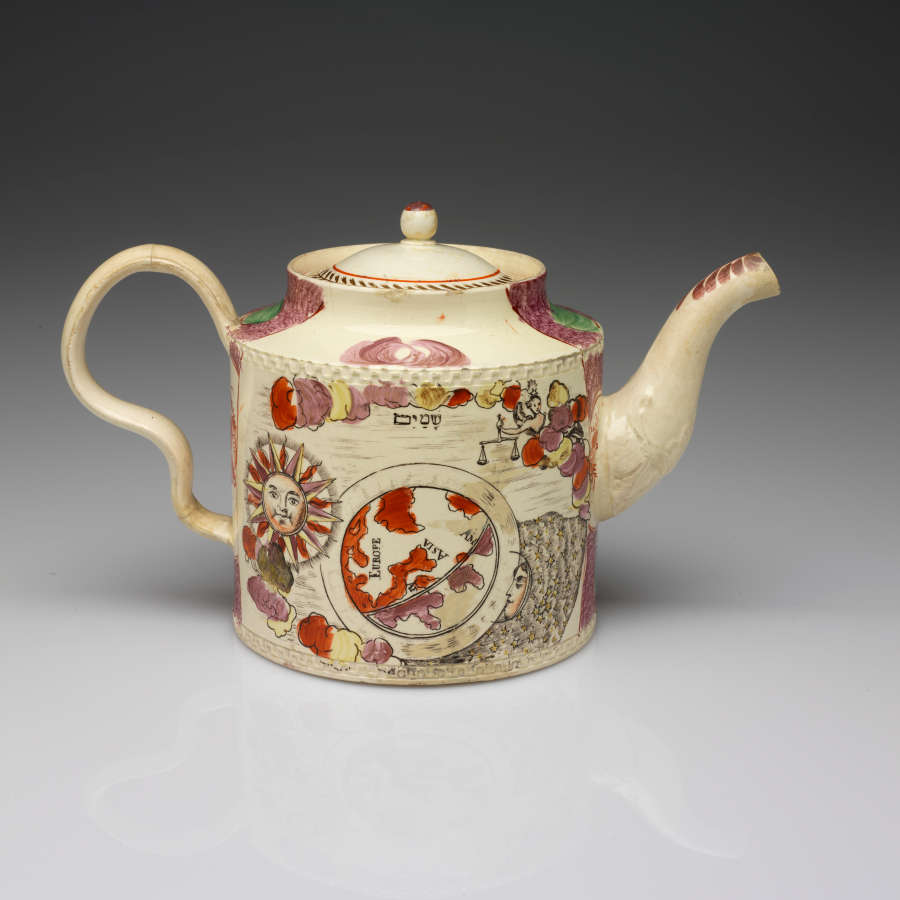 A cylindrical teapot with an inward curve towards the lid, a wavy handle, and a spout. The transfer printed decorations are a sun, a map, and a figure holding scales.