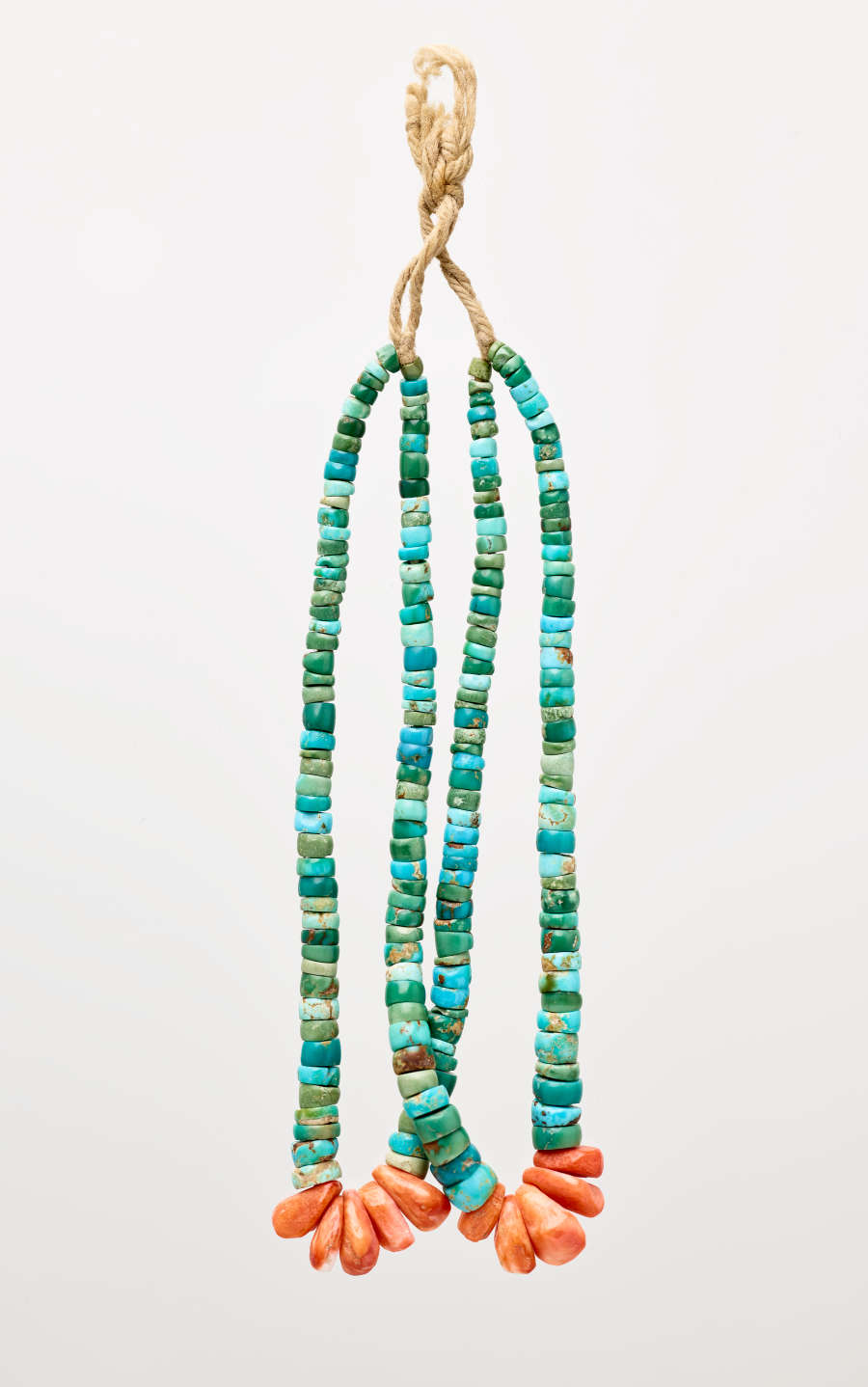 Earring with a twine-like hook connecting to two loops of flat, circular turquoise beads, with kernel-like red beads at each loop’s base.