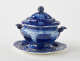  A dark blue decorative sauce boat. Two symmetrical sculptural handles that depict a bird’s head, foot, and lid with rounded finial