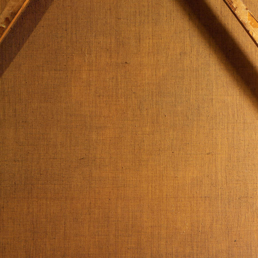 Close-up of warm brown-toned canvas, revealing its fine woven texture with wooden braces partially visible in the upper corners, casting slight shadows.