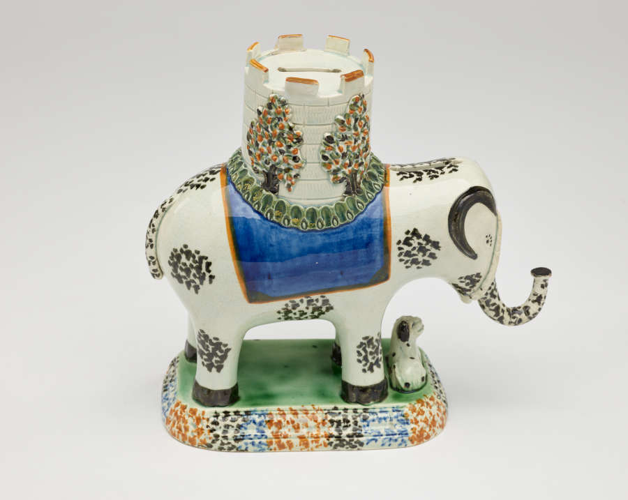  A sculpture in the shape of an elephant with a castle on its back. The decorations are white, blue, green, and yellow.
