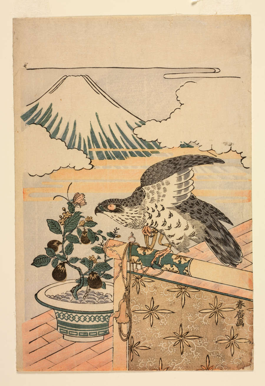 Woodblock print of a flowering and fruiting potted plant behind a hawk perched on an ornamented wooden rod. In the distance, Mount Fuji peeks from behind fluffy white clouds. 