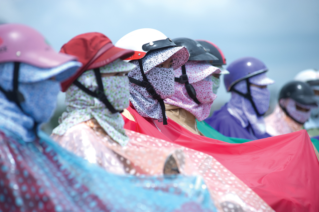 people on scooters wearing colorful helmets, colorful ponchos, and floral face masks