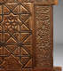 A close-up of a carved wooden panel featuring intricate geometric star patterns on the left and detailed floral motifs along the right edge.