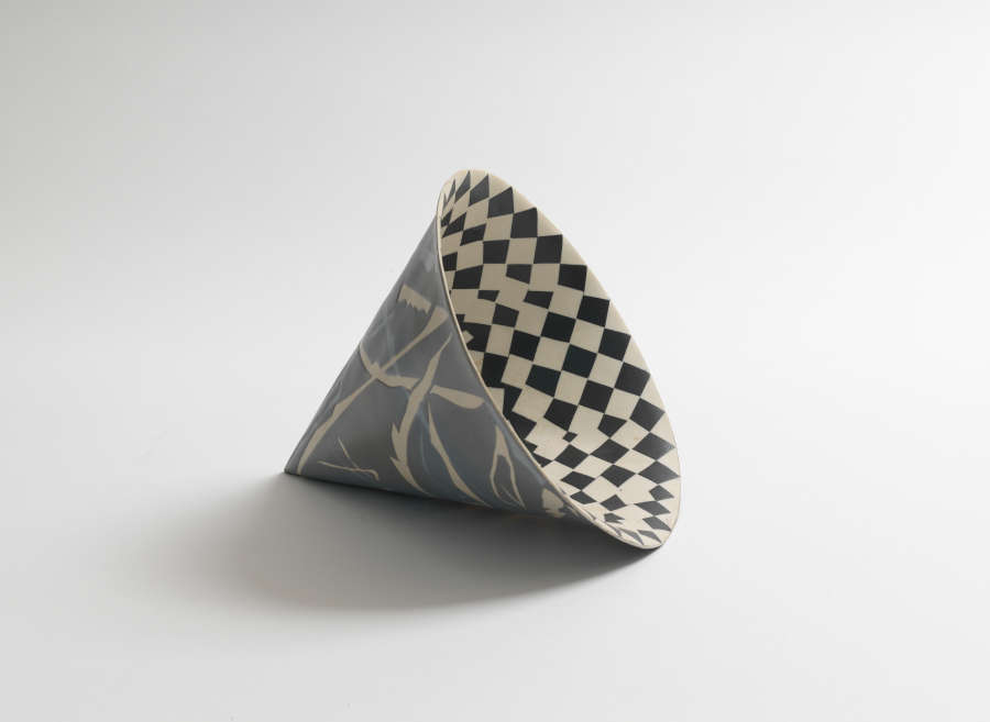 A hollow cone structure tipped to the side, with a checkered pattern on the interior and abstracted white branches on a dark exterior. 