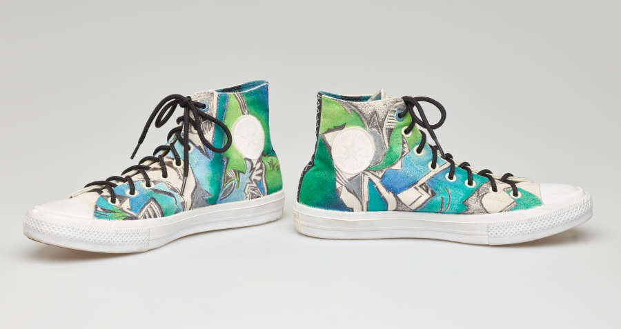 A pair of hand-painted high-top sneakers in shades of blue-green. The shoes face away from each other, revealing a white circle where a logo should be on the outer side.