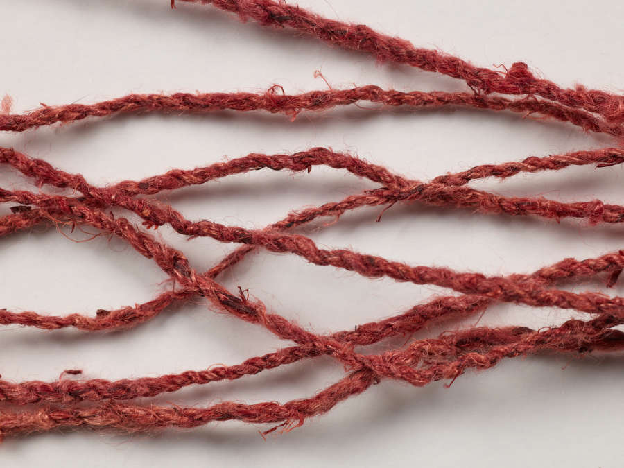 Detail-view of the warp threads of a purple and white beaded belt, braided to be thicker than the thinner white weft.