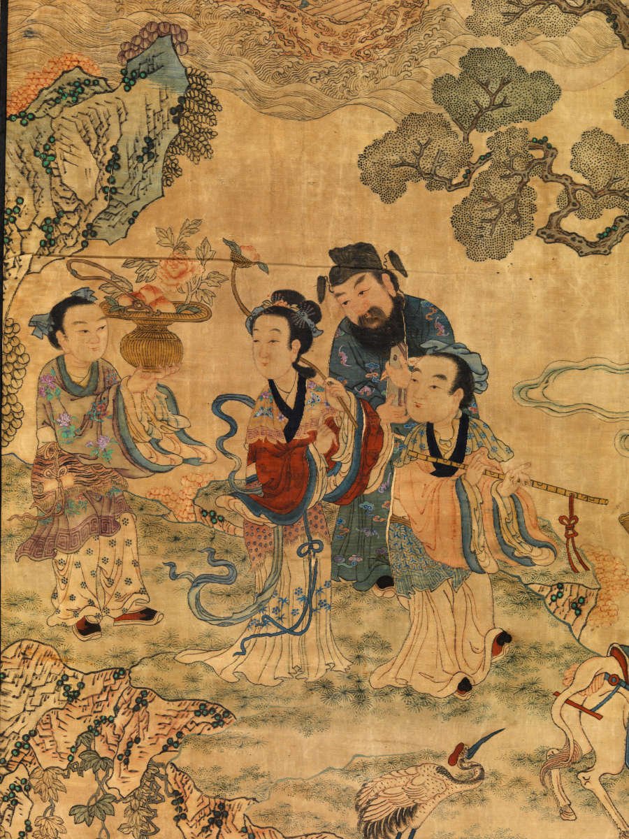 Detail of a group of robed figures standing with one figure playing the flute, together on the grassy edge of a cliff, surrounded by trees, clouds, and birds.