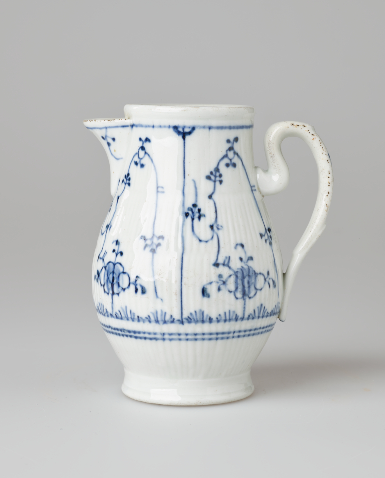 A white chocolate pot with delicate blue decorations with ribbed body, spout, handle, and foot.